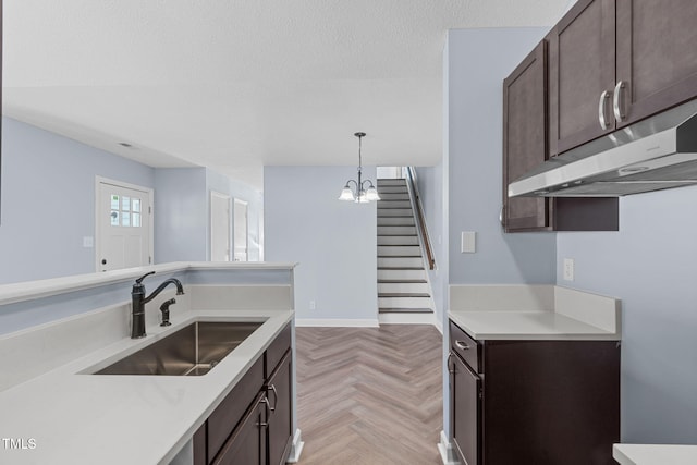 kitchen featuring light parquet floors, sink, hanging light fixtures, a notable chandelier, and dark brown cabinetry