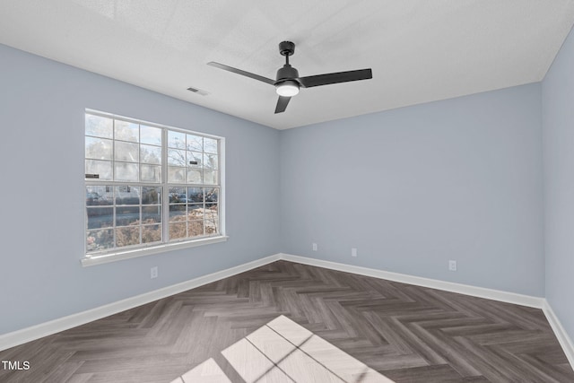 empty room featuring dark parquet floors, ceiling fan, and a textured ceiling