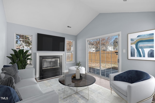 living room with light wood-type flooring, plenty of natural light, and lofted ceiling