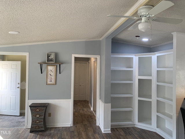 corridor featuring built in features, dark hardwood / wood-style flooring, a textured ceiling, and ornamental molding