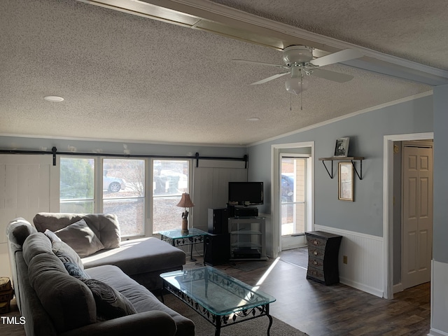 living room with ceiling fan, dark wood-type flooring, a barn door, lofted ceiling, and ornamental molding