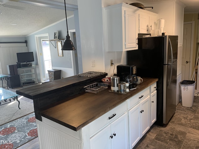 kitchen featuring crown molding, white cabinets, wooden counters, and decorative light fixtures