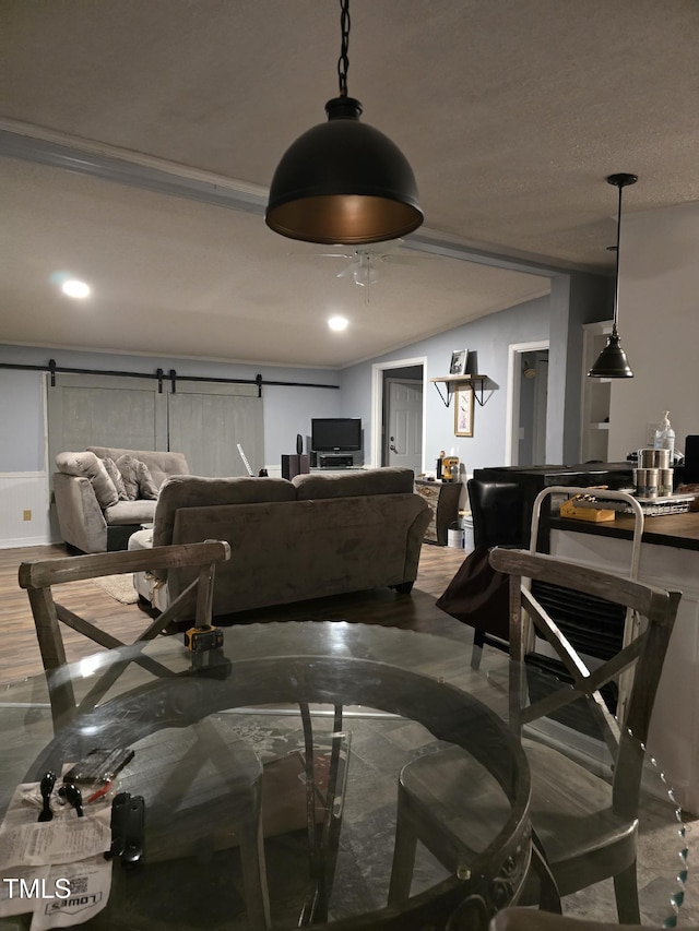 living room featuring a textured ceiling, a barn door, hardwood / wood-style flooring, and vaulted ceiling