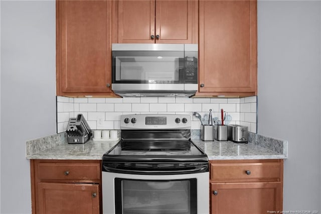 kitchen featuring light stone counters, stainless steel appliances, and tasteful backsplash