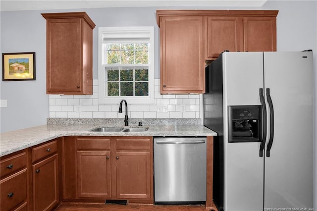 kitchen with decorative backsplash, sink, light stone countertops, and appliances with stainless steel finishes