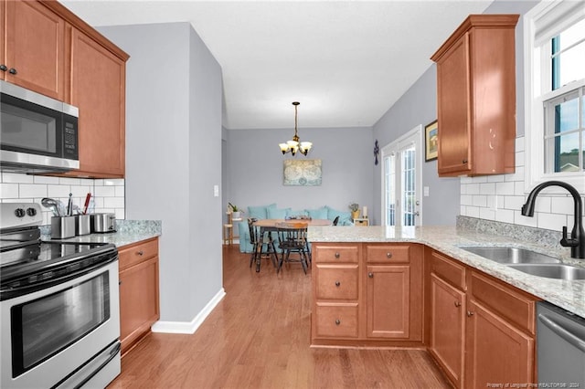 kitchen with sink, stainless steel appliances, tasteful backsplash, a notable chandelier, and light wood-type flooring