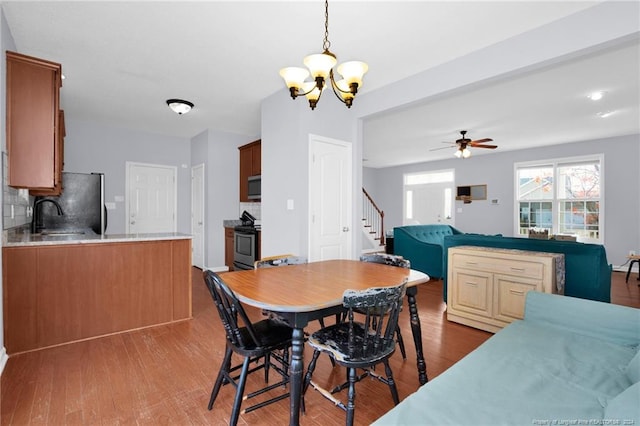 dining room with ceiling fan with notable chandelier, wood-type flooring, and sink