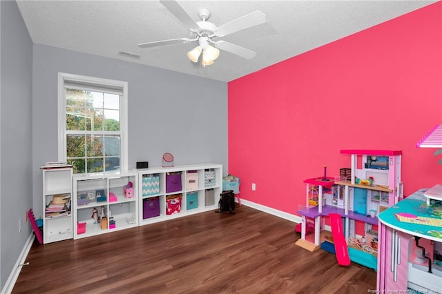 recreation room featuring a textured ceiling, ceiling fan, and dark wood-type flooring