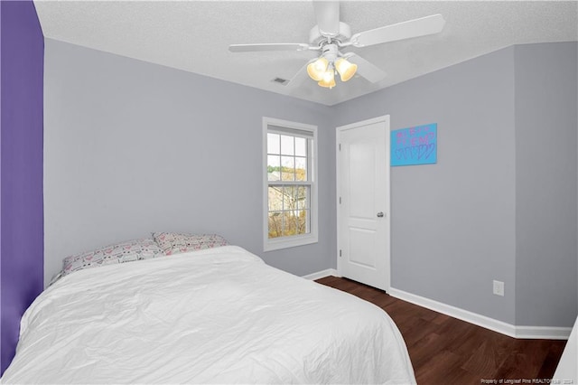 bedroom with ceiling fan, dark wood-type flooring, and a textured ceiling