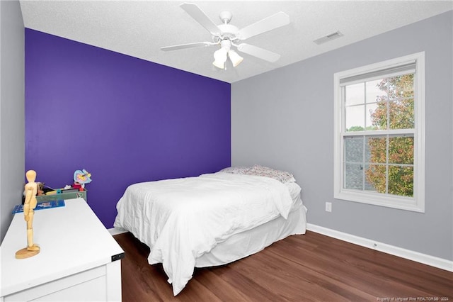 bedroom featuring a textured ceiling, dark hardwood / wood-style floors, and ceiling fan