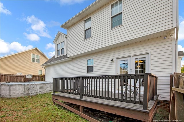 rear view of property with a swimming pool side deck and a yard