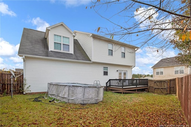 rear view of house with a swimming pool side deck and a yard