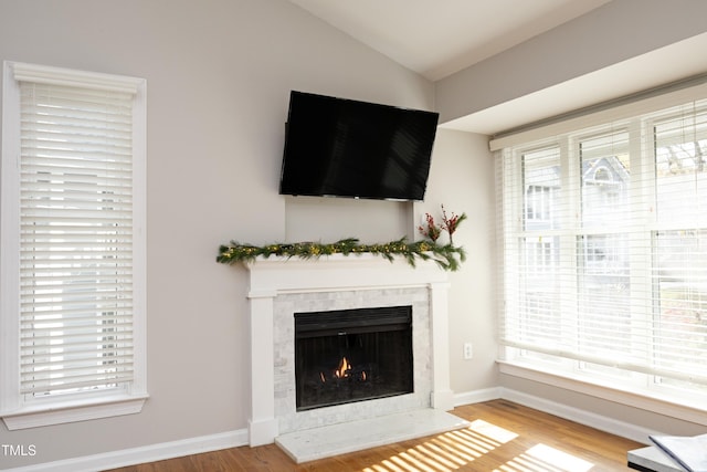 unfurnished living room with hardwood / wood-style floors, plenty of natural light, and a premium fireplace