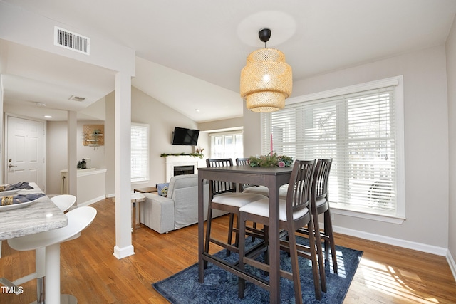 dining area featuring hardwood / wood-style floors, vaulted ceiling, and a wealth of natural light