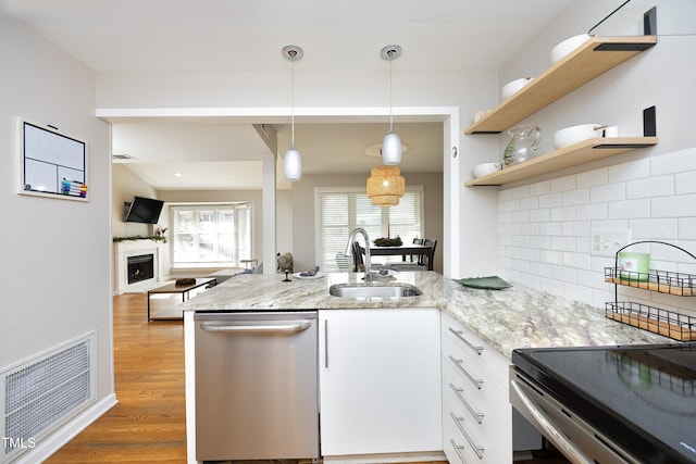 kitchen with light stone counters, stainless steel dishwasher, sink, decorative light fixtures, and white cabinets