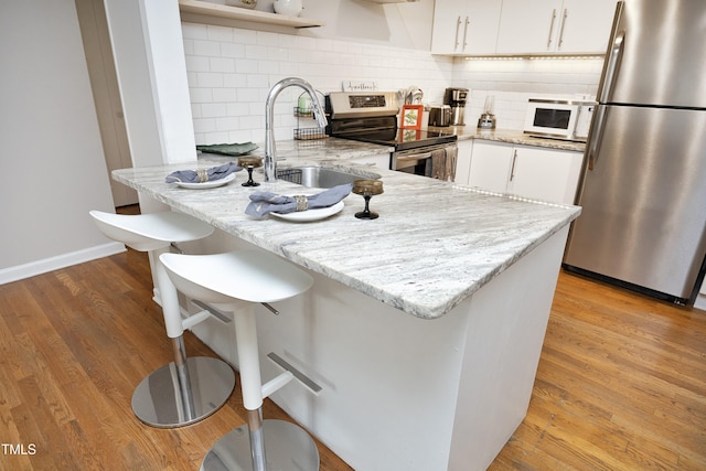 kitchen with white cabinetry, sink, light hardwood / wood-style flooring, kitchen peninsula, and appliances with stainless steel finishes