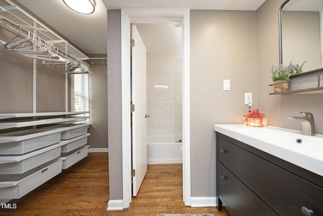 bathroom with hardwood / wood-style floors, vanity, and tiled shower / bath