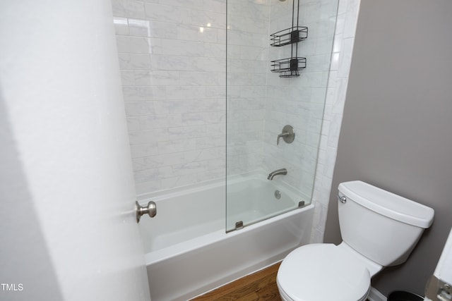 bathroom featuring hardwood / wood-style floors, tiled shower / bath, and toilet