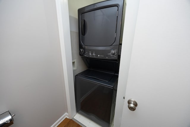 washroom with hardwood / wood-style floors and stacked washer and clothes dryer