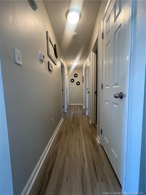 hallway featuring hardwood / wood-style floors and a textured ceiling