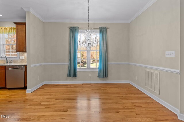 unfurnished dining area with sink, an inviting chandelier, ornamental molding, and light wood-type flooring