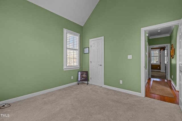 unfurnished bedroom with high vaulted ceiling, crown molding, and light colored carpet