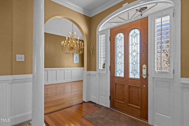 entryway featuring crown molding, plenty of natural light, wood-type flooring, and a chandelier