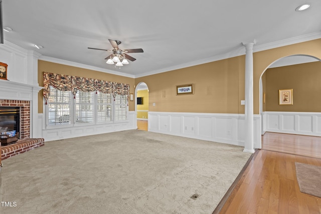 unfurnished living room with light hardwood / wood-style flooring, a fireplace, ornamental molding, and ceiling fan