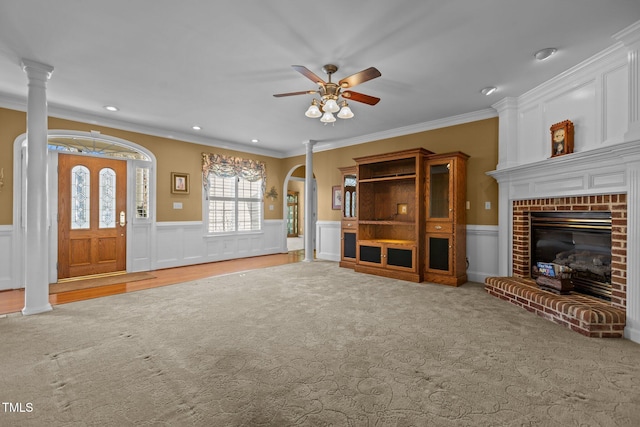 unfurnished living room featuring ornate columns, crown molding, a brick fireplace, and carpet floors