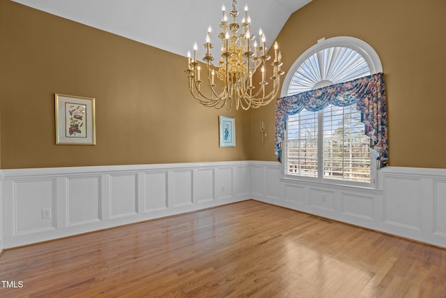 unfurnished room featuring lofted ceiling, an inviting chandelier, and light hardwood / wood-style flooring