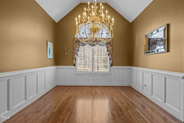 unfurnished room with lofted ceiling, a notable chandelier, and light wood-type flooring