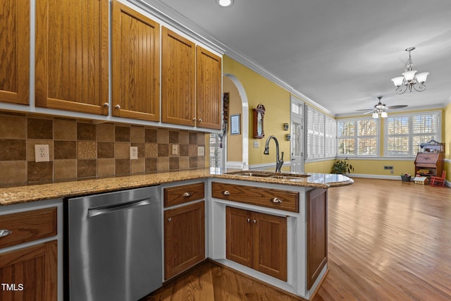 kitchen featuring sink, light stone counters, stainless steel dishwasher, ornamental molding, and kitchen peninsula