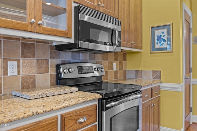 kitchen featuring tasteful backsplash, light stone countertops, and appliances with stainless steel finishes