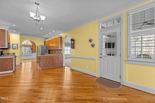 kitchen featuring stainless steel appliances, crown molding, light wood-type flooring, and a chandelier