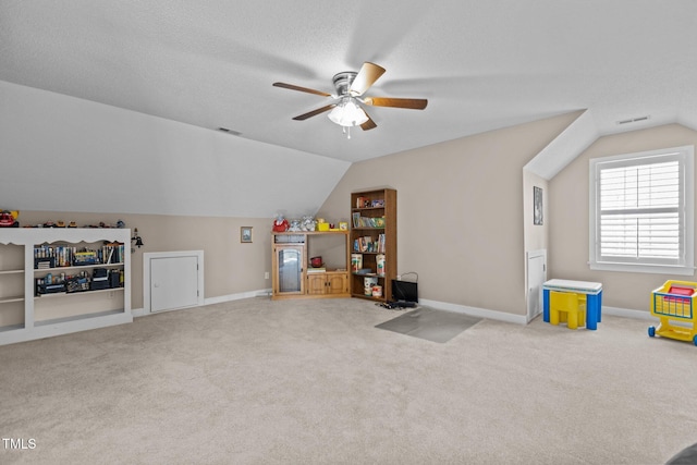 game room featuring vaulted ceiling, light colored carpet, ceiling fan, and a textured ceiling