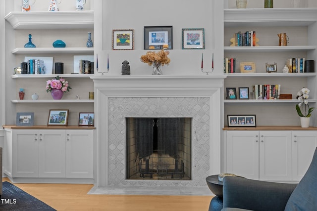 living room featuring a tiled fireplace and light hardwood / wood-style floors