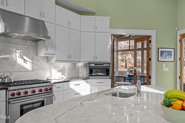 kitchen with tasteful backsplash, white cabinetry, sink, stainless steel appliances, and light stone countertops