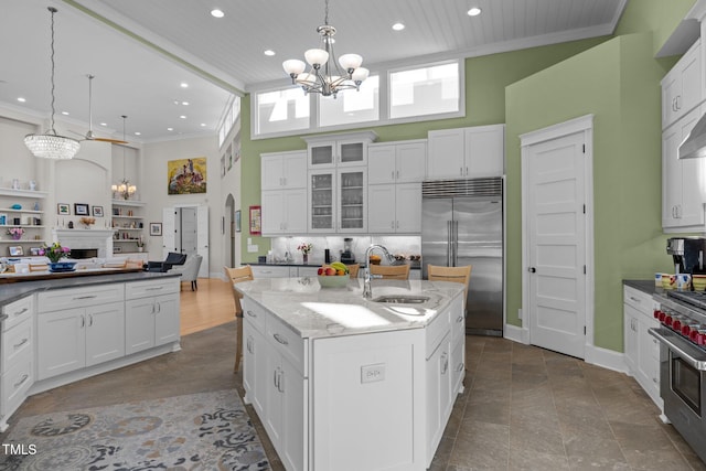 kitchen featuring decorative light fixtures, white cabinets, a chandelier, high end appliances, and a kitchen island with sink