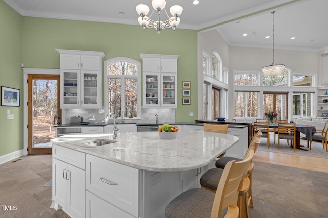 kitchen featuring pendant lighting, sink, an island with sink, and an inviting chandelier