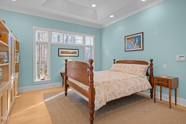 bedroom featuring a tray ceiling and light hardwood / wood-style flooring