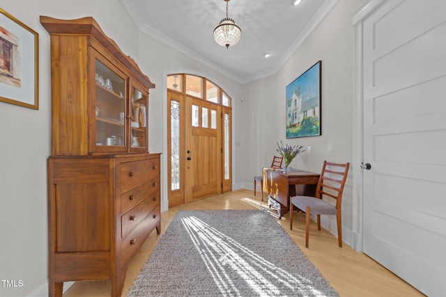 entryway with ornamental molding and light hardwood / wood-style floors