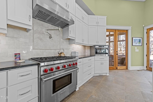 kitchen with appliances with stainless steel finishes, ventilation hood, white cabinets, backsplash, and french doors