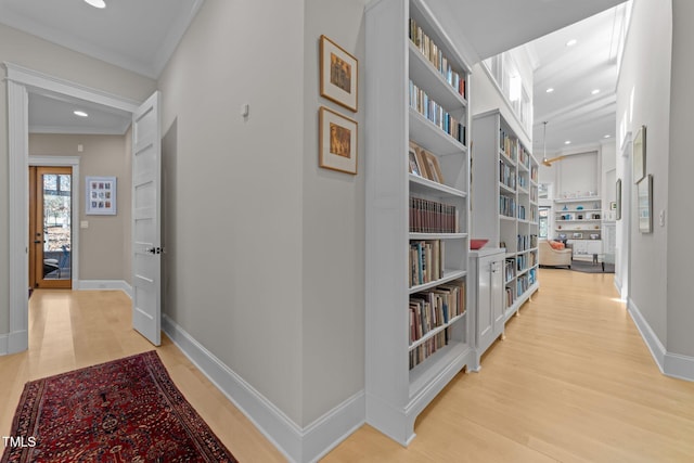 hallway with ornamental molding, built in features, and light wood-type flooring