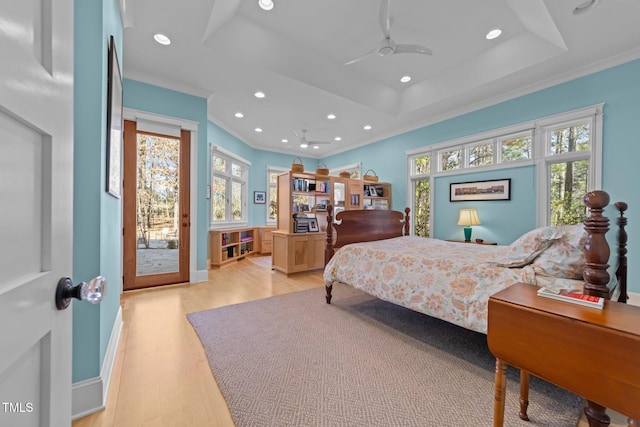 bedroom featuring crown molding, a raised ceiling, light hardwood / wood-style flooring, and access to outside