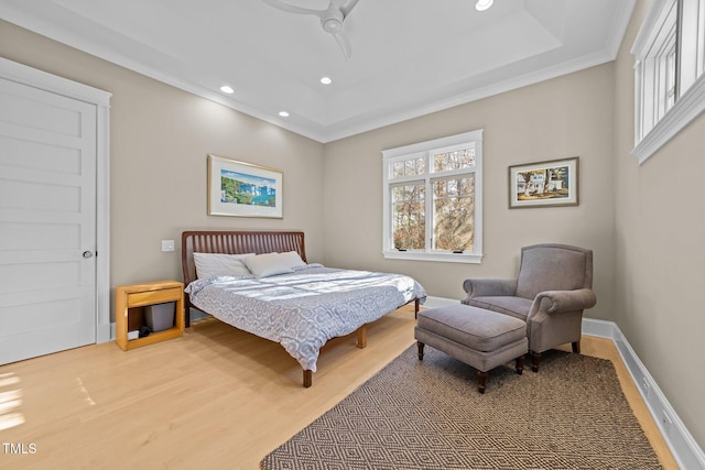 bedroom with a raised ceiling, hardwood / wood-style floors, and ceiling fan