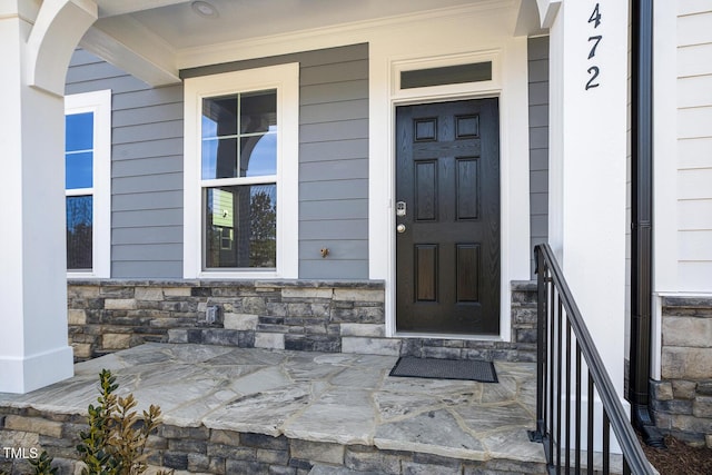 view of exterior entry with stone siding and a porch