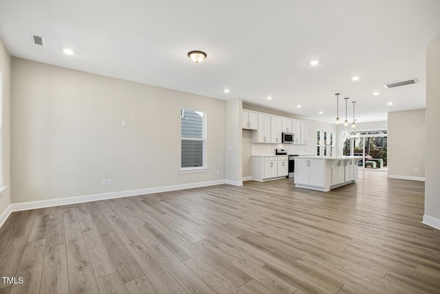 unfurnished living room with baseboards, visible vents, and light wood-style floors