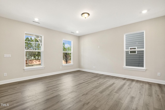 spare room with baseboards, visible vents, dark wood-style flooring, and recessed lighting