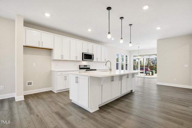 kitchen featuring white cabinets, stainless steel appliances, wood finished floors, and light countertops