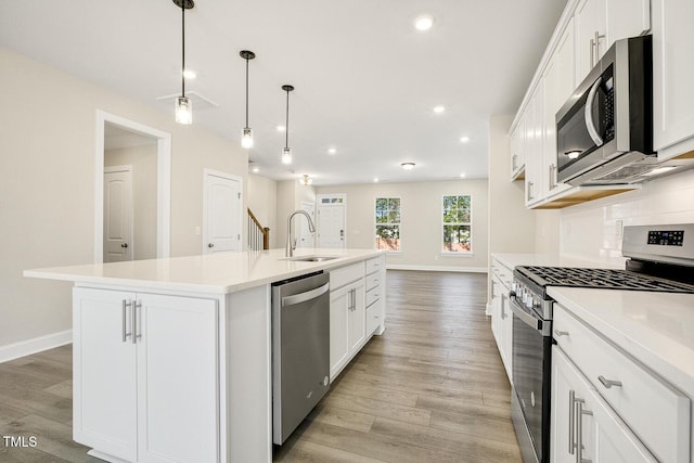 kitchen featuring tasteful backsplash, stainless steel appliances, a sink, and light wood-style flooring